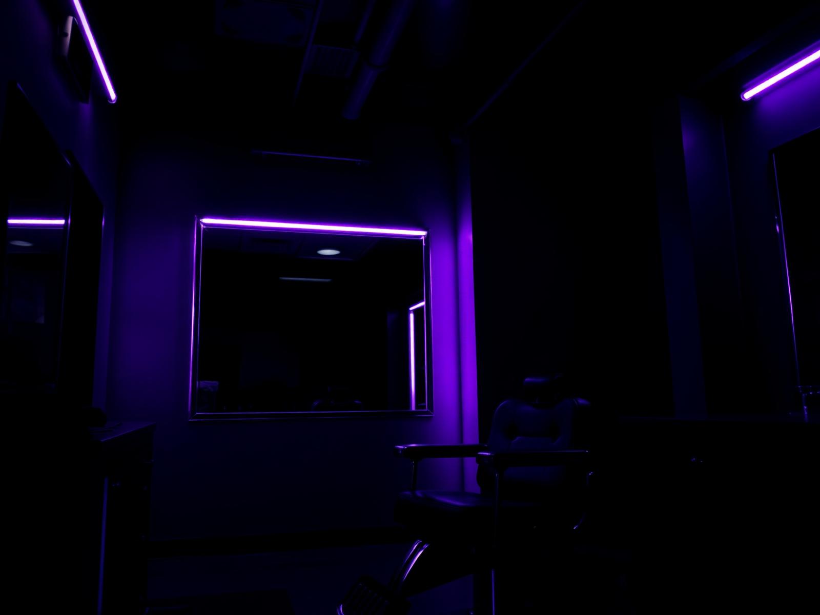 Moody premium barbershop interior lit with violet accents